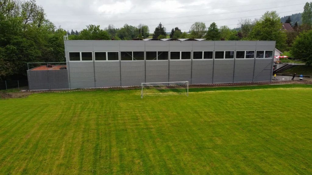 Noch ist nicht klar, ob es für die Bezahlung aller Rechnungen für den Bau noch Geld braucht. Eine Turnhalle hinter einem Fussballplatz.